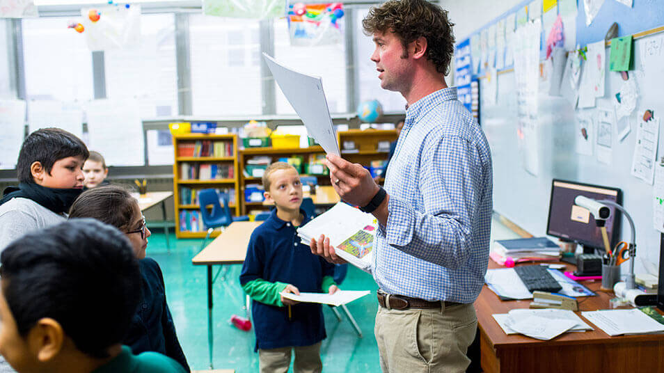 A School of Education student stands in the front of an elementary school classroom answering questions