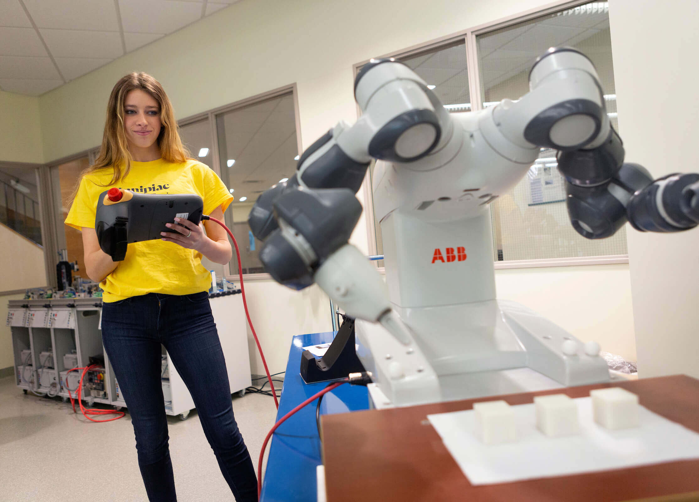 A female student operates a remote for a robot