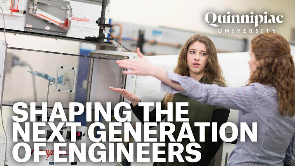 Two engineering students gesturing toward equipment in a lab, starts video