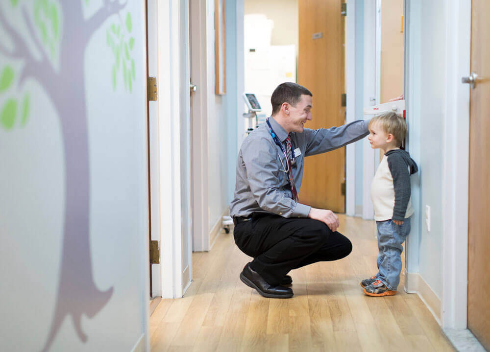 A physician assistant student measures a child's height in a pediatrician office