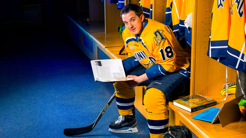 Soren Jonzzon sitting in the locker room wearing his Quinnipiac hockey uniform