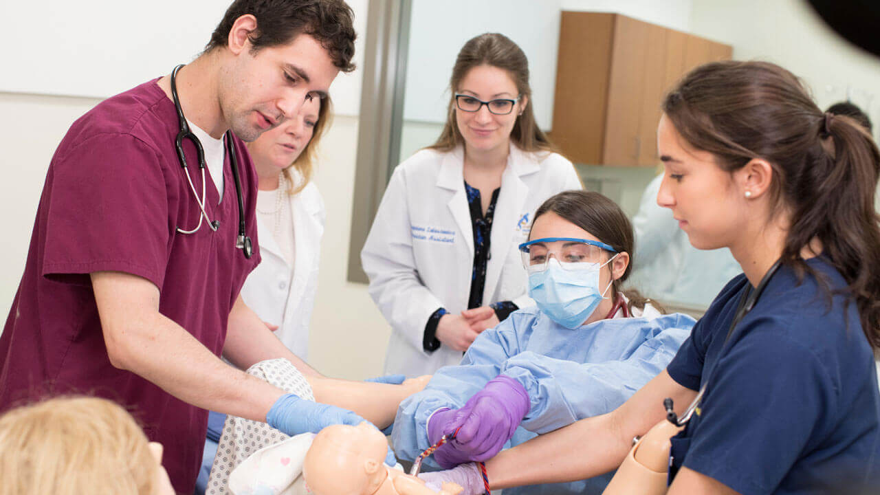 A group of students participate in a newborn delivery simulation