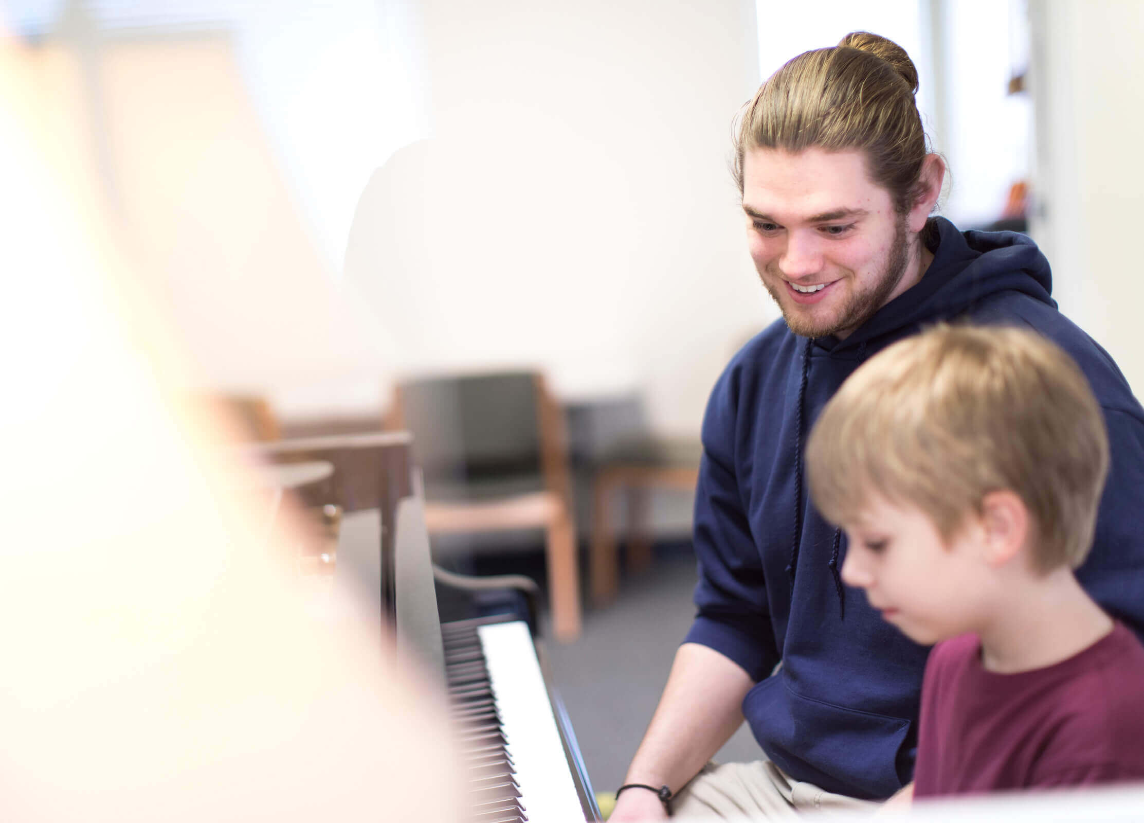 A student helps a toddler play the piano