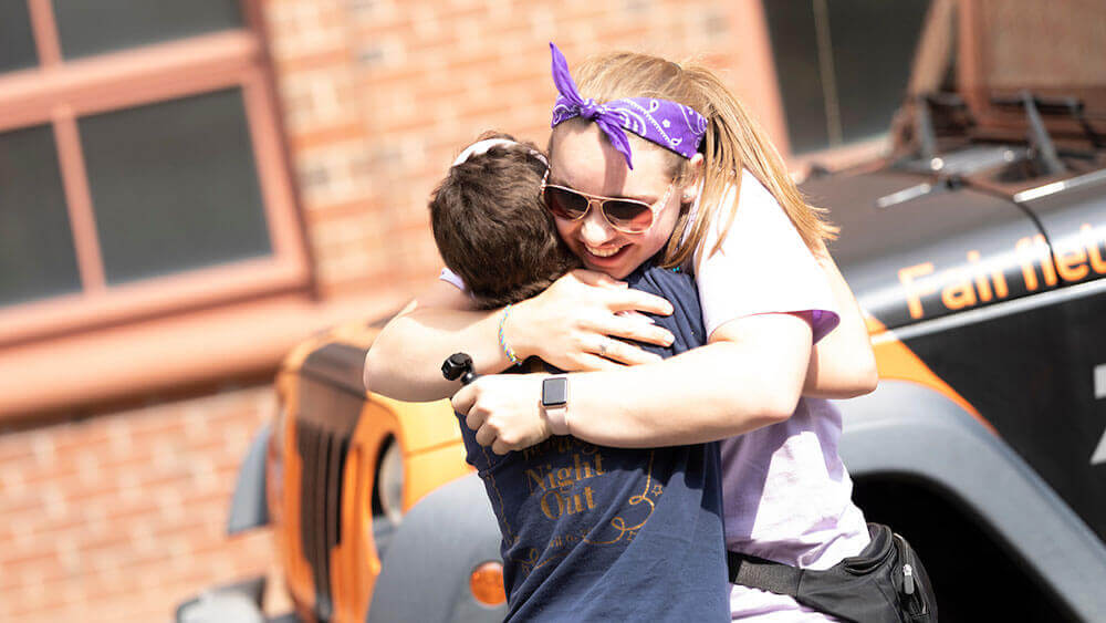 A health sciences student hugs a camp attendee
