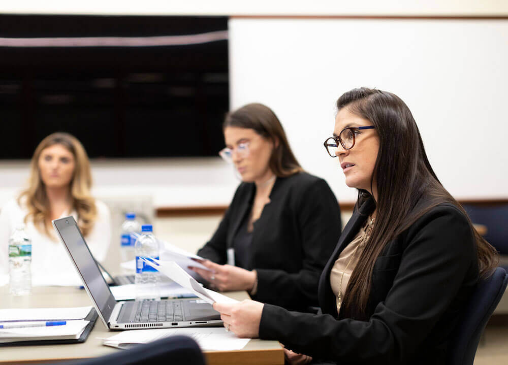 Three law students listen intently to a law workshop