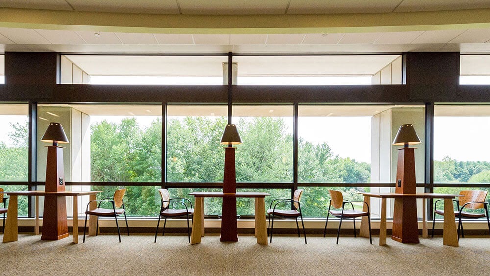 Shot of tables and chairs in a study area with large windows looking out on the North Haven Campus