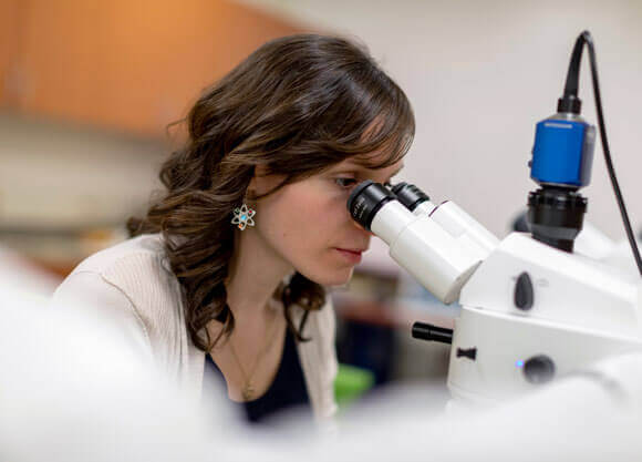 A student looks through a microscope