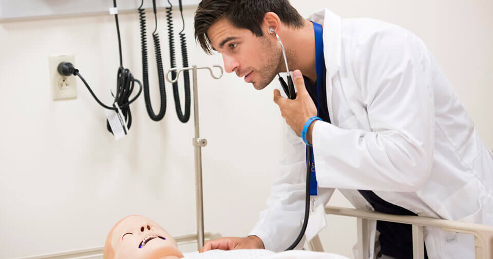 A nursing student listens to the heartbeat of a simulation mannequin