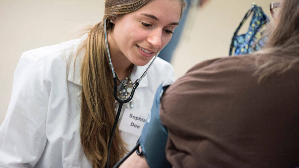 A nursing student checks a patient's blood pressure