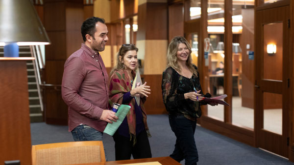 A student walks with faculty and staff in the law library