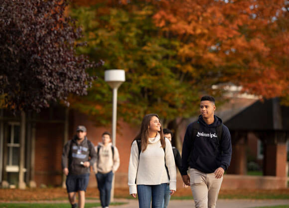 Two undergraduate students walk across the Mount Carmel Campus quad