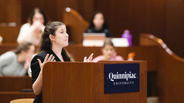 A student speaks at a podium in the Ceremonial Courtroom