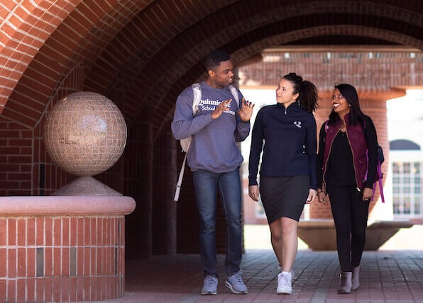 Three business students walk on campus.