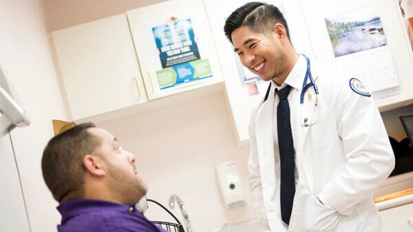 A medical student speaks with a patient in a doctor's office