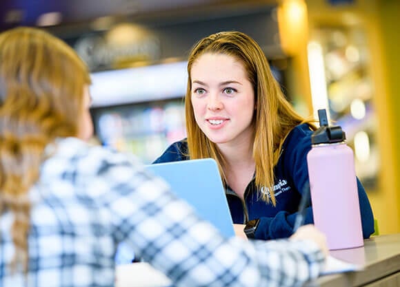 woman talking in library to another woman
