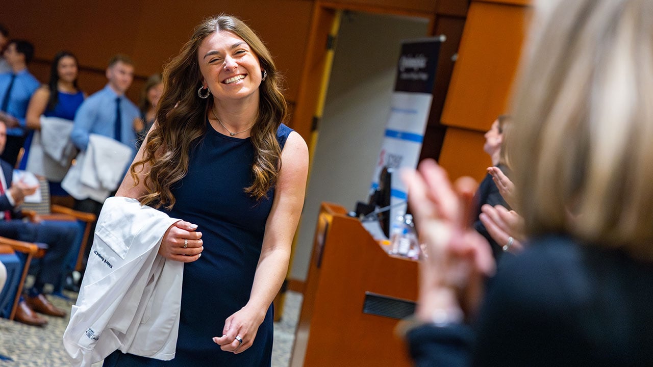 Student smiles at White Coat Ceremony