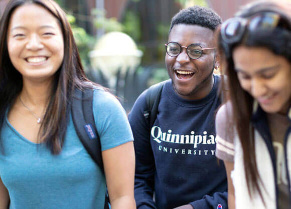 Three students walking and smiling on campus