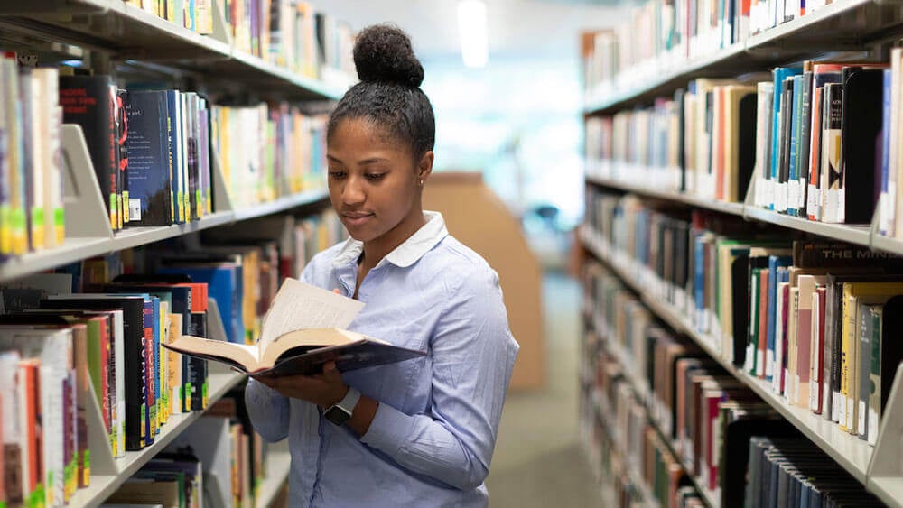Quinnipiac University Orientation Leader Myriam Dabuisson ’22, reads in the Arnold Bernhard Library on the Mount Carmel Campus