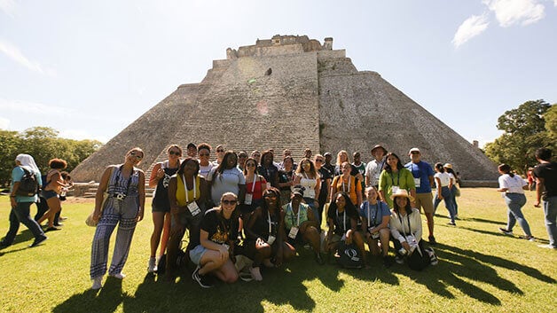 A group of students take a group photo in Uxmal.
