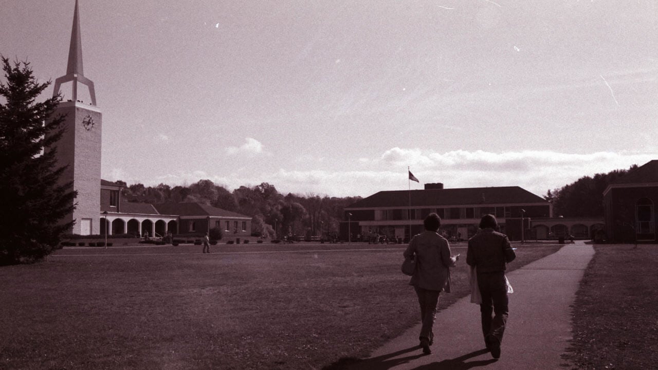Two students walk across the Quinnipiac quad in 1977