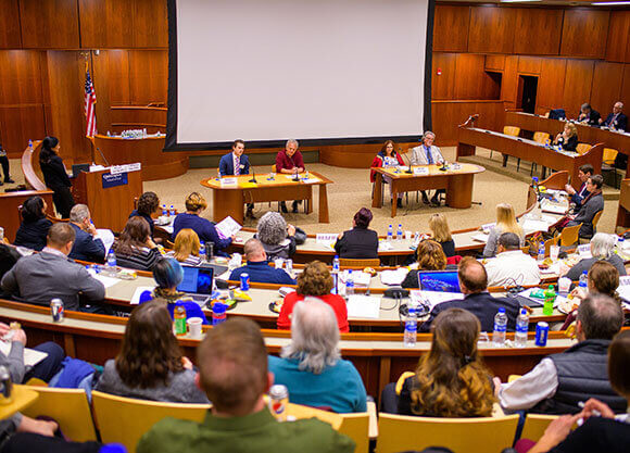 People sit in the school of law's ceremonial courtroom listening to a panel of speakers.