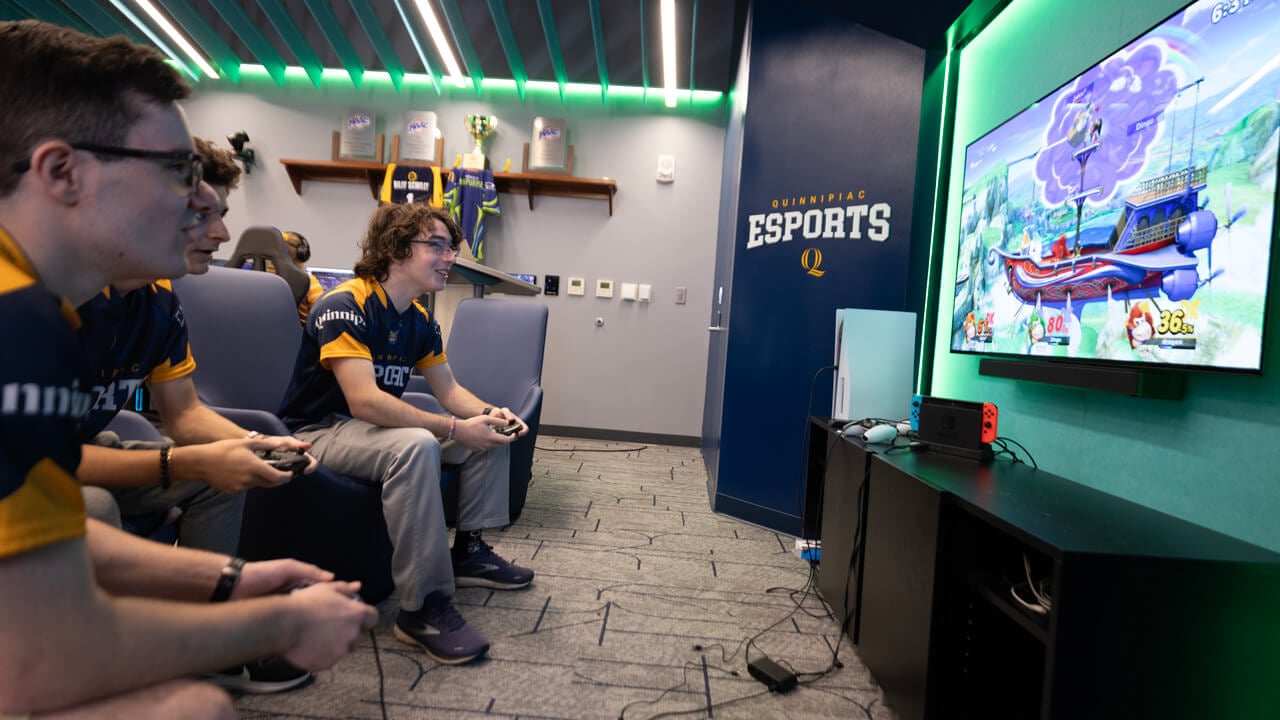 3 esports athletes play a video game on a large screen