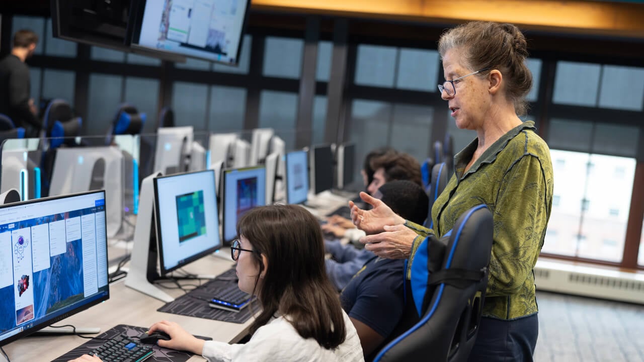 A female professor instructs students in the esports lab