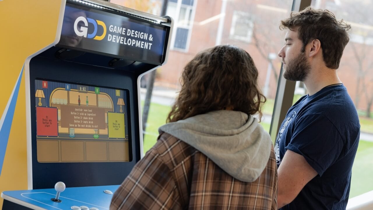 Two people playing a game on a Quinnipiac Game Design and Development arcade cabinet
