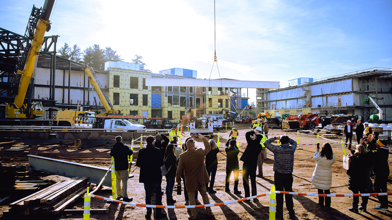 A group of QU staff take photos of a beam being placed on a building on the South Quad.