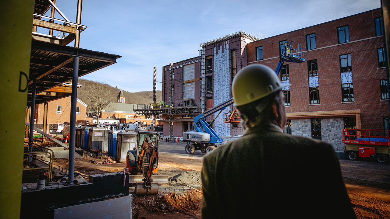 A construction worker's head is blurred out as the focus is on a south quad building in the background.
