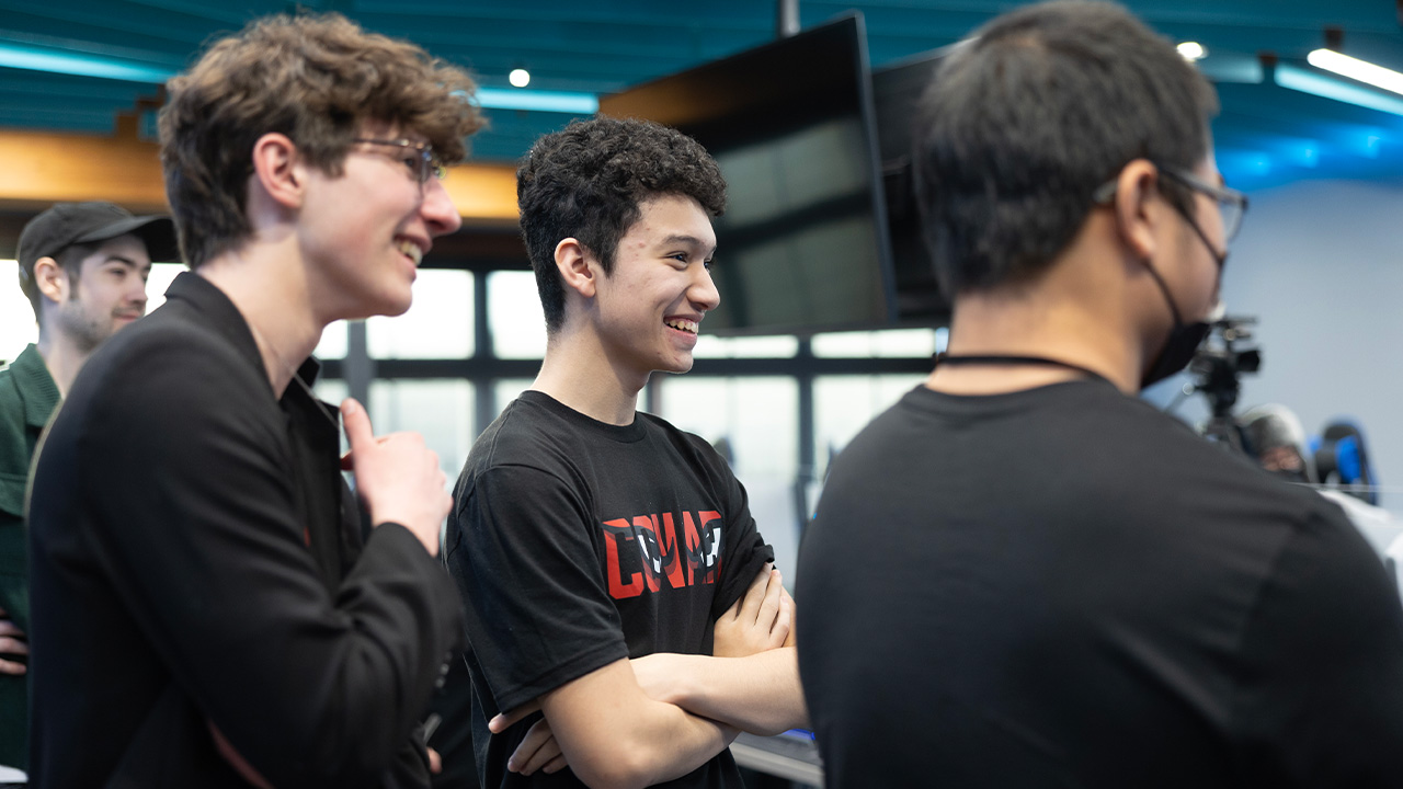 eSports Athletes stand in a group, smiling, watching their teammates.