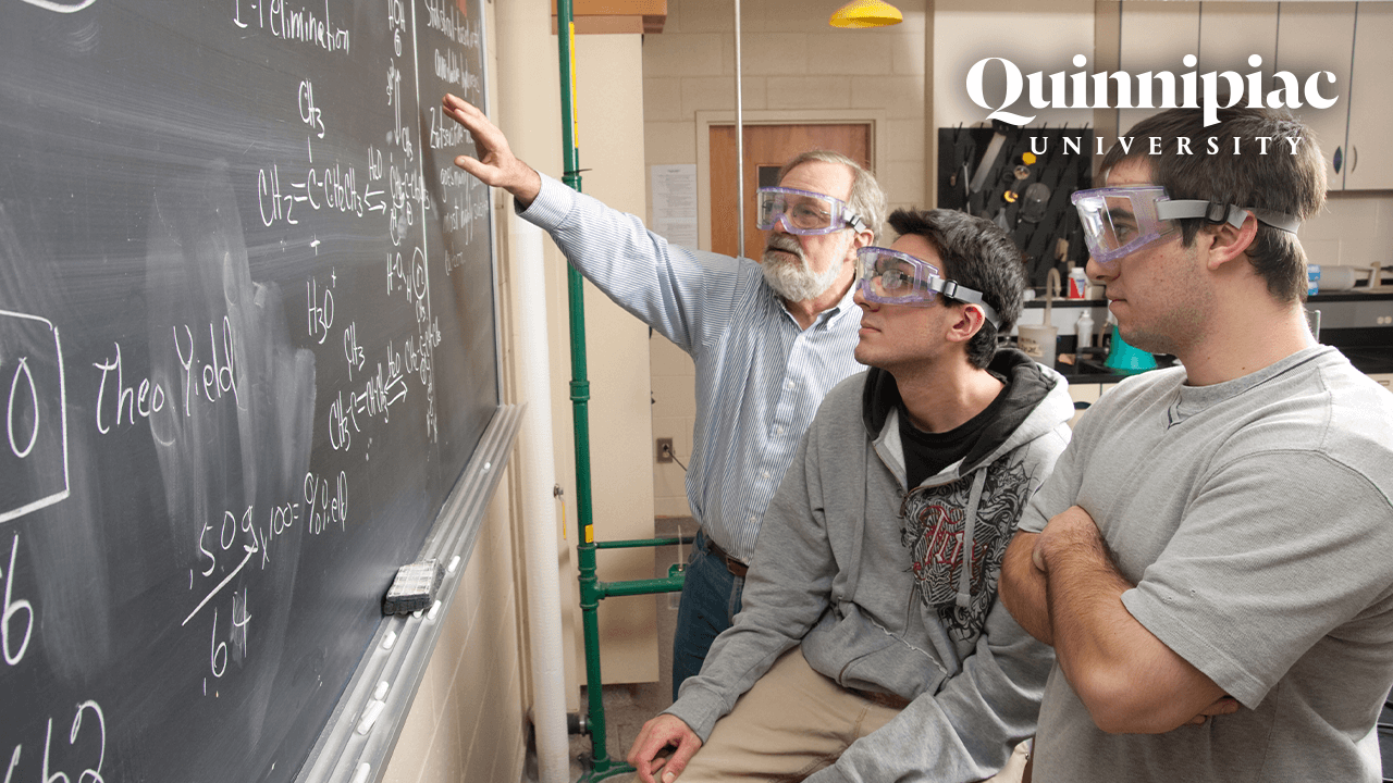 Students and professor look at an equation on a chalkboard