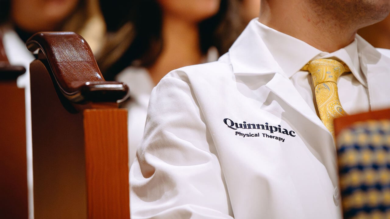 An up-close shot of a student’s white coat that reads “Quinnipiac Physical Therapy”