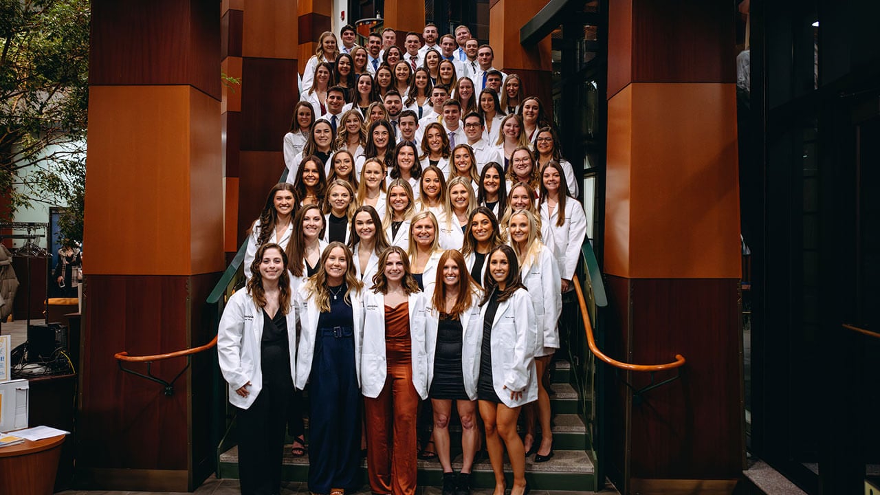 A group photo of all the white coat DPT students of 2023 standing on stairs at the North Haven campus.