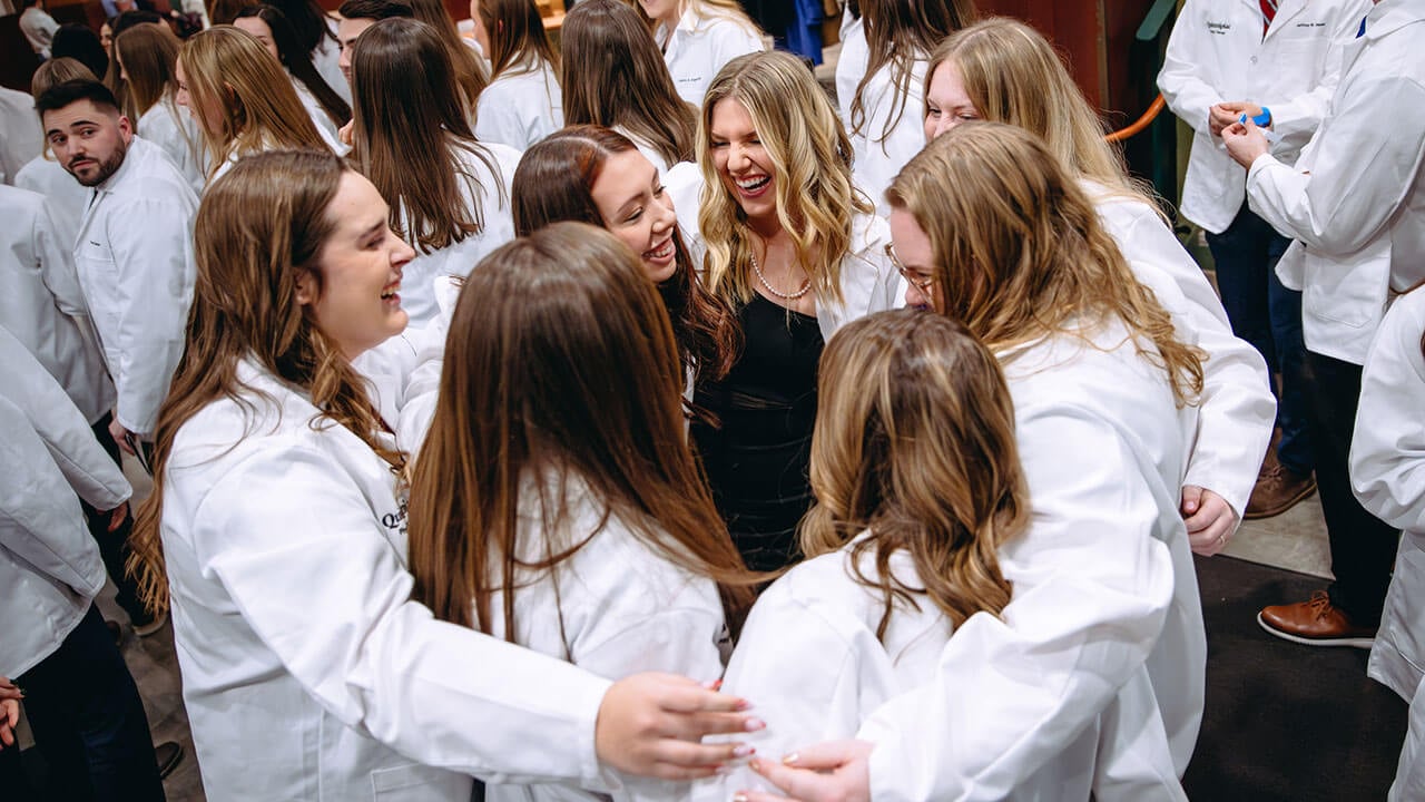 A group of DPT white coat students circling up for a group hug