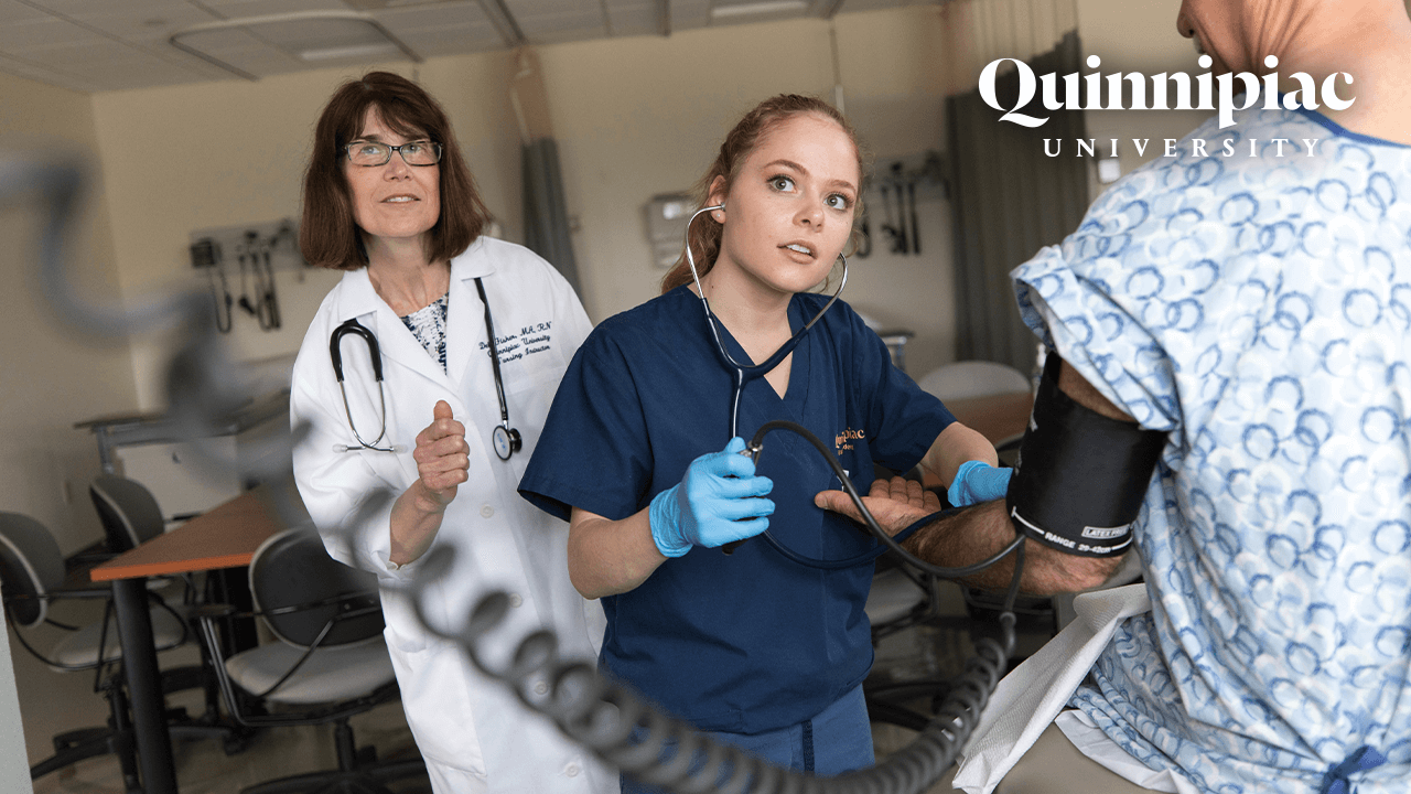 A nursing student wearing scrubs checks a patient's blood pressure