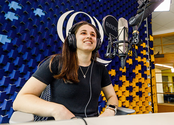 girl sitting in the podcast studio with headphones and a microphone